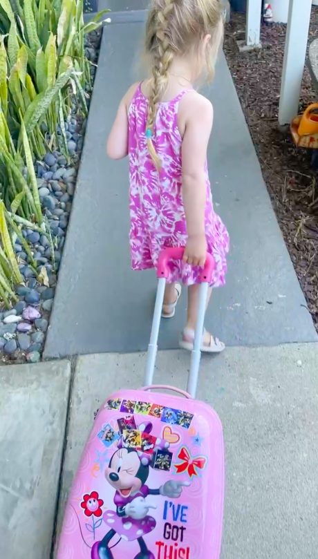 toddler girl with rolling suitcase