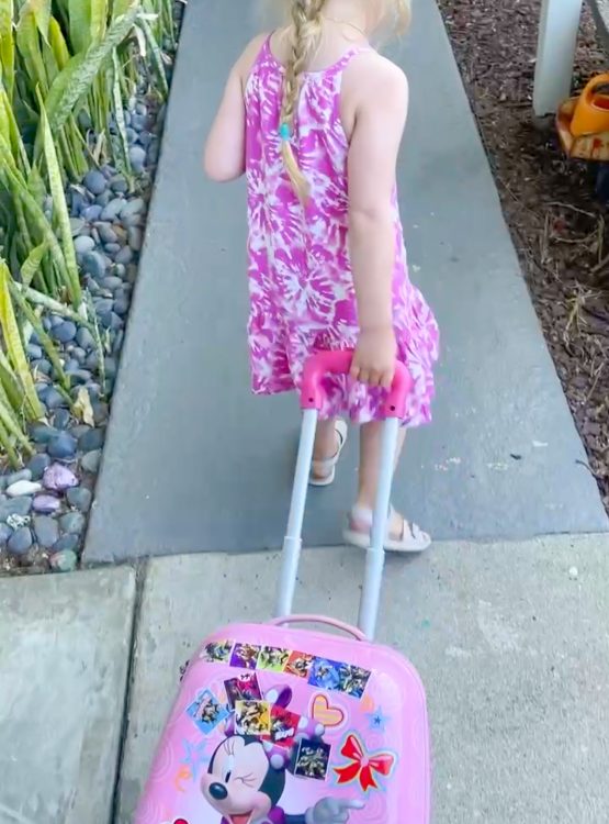 toddler girl with rolling suitcase